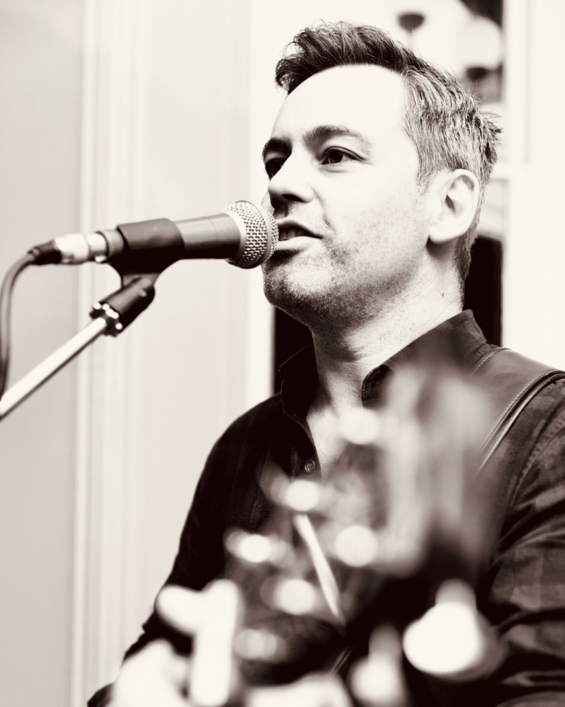 Close-up of Ballarat musician Dan West performing with microphone and guitar for Sunday Session at The Courthouse Hotel Smythesdale.