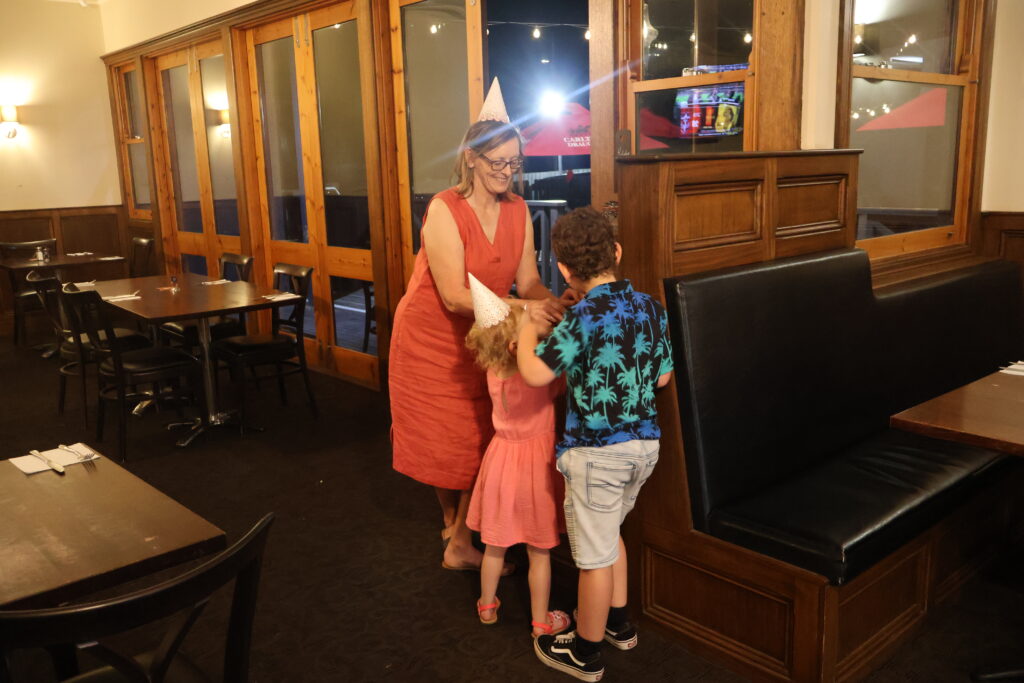 Mother and two young children in party hats playing together in the dining room at The Courthouse Hotel Smythesdale during a family-friendly celebration.